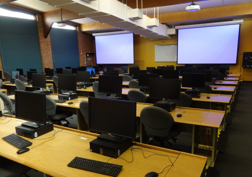 Oregon building computer lab with desks, computers, chairs, and screens in the front