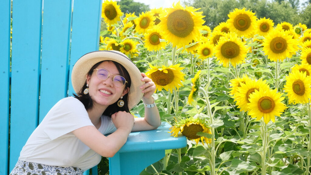 Huaqi smiling in front of sunflowers